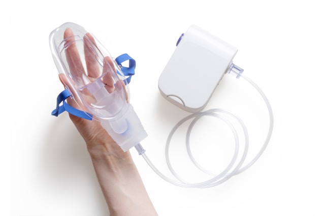 Hand holding a CPAP mask connected to a sleep apnea therapy device.