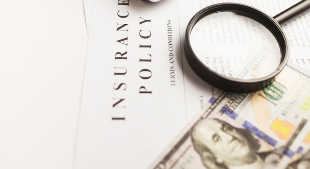 Insurance policy documents and a magnifying glass on a table.