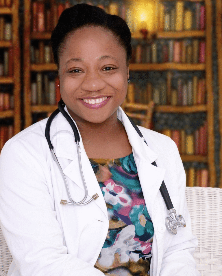 Dr. Asha Inniss, DNP, wearing a stethoscope and white lab coat in front of a bookshelf.