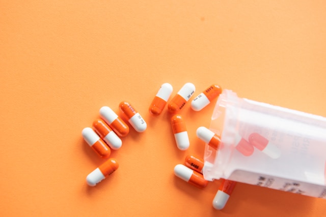 Prescription medication orange pill bottles and scattered capsules on a warm background.