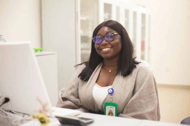 Smiling healthcare professional sitting at a desk with a laptop.